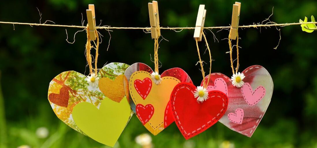 Three brightly colored hearts strung up on a laundry line.