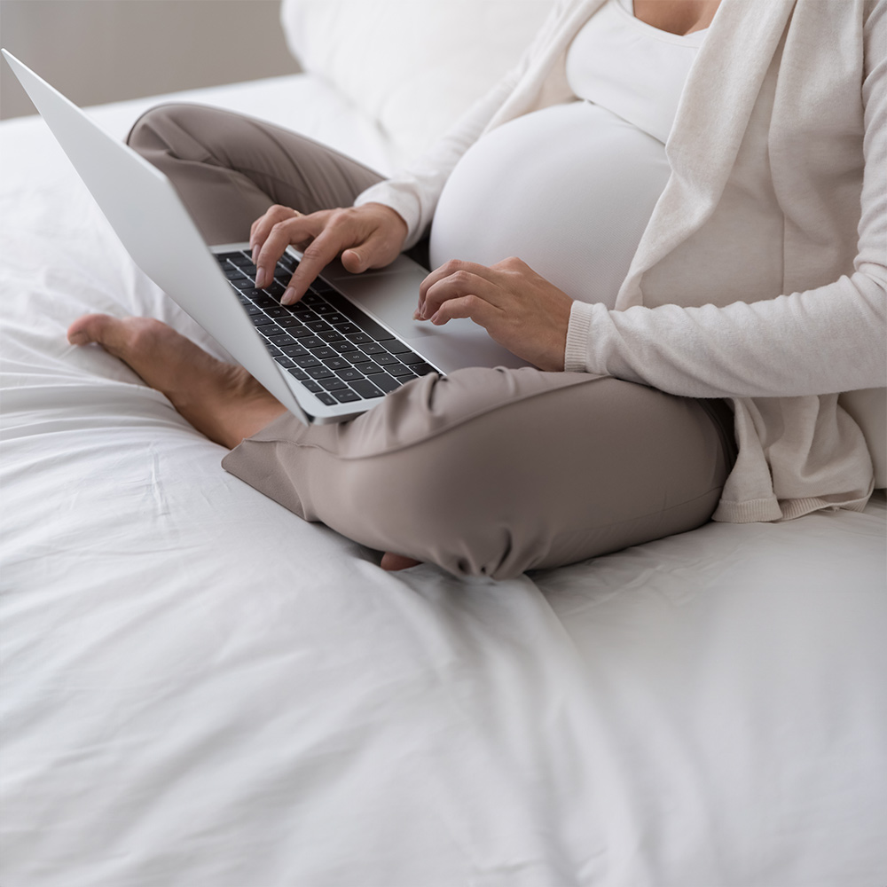 Pregnant woman on a computer getting video therapy from a San Diego Therapist.